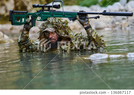 Camouflaged Sniper Soldier Wading Through Water Holding Rifle Above Head During Reconnaissance Camouflaged Sniper Soldier Wading Through Water Holding Rifle Above Head During Reconnaissance 136867117
