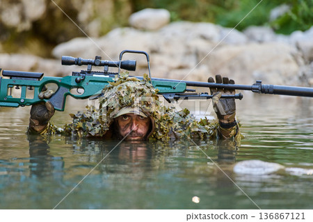 Camouflaged Sniper In Water With Rifled Scope Peering From Ghillie Suit During Tactical Recon Mission Camouflaged Sniper In Water With Rifled Scope Peering From Ghillie Suit During Tactical Recon Mission 136867121