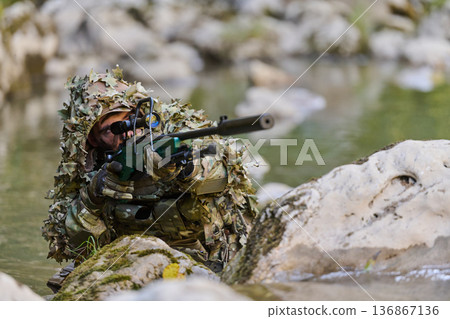 Camouflaged Sniper Soldier In Ghillie Suit Aiming Rifle While Concealed In Stream Camouflaged Sniper Soldier In Ghillie Suit Aiming Rifle While Concealed In Stream 136867136