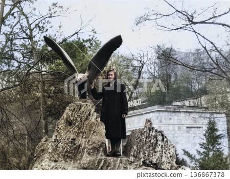 A vintage portrait of a beautiful young girl near an eagle statue in Kislovodsk. Retro photo, 1958. 136867378