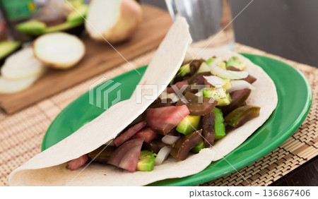 salad of black tomatoes, avocado and onions in Italian tortilla on green plate salad of black tomatoes, avocado and onions in Italian tortilla on green plate 136867406