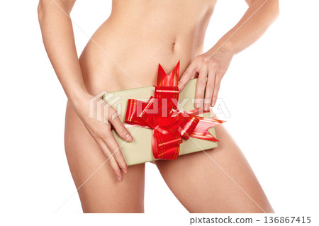 Sensual close up of female hips and beautiful body holding gift box with red ribbon covering intimate area, concept of surprise, romance, sexuality, femininity, provocative present, passion, erotic Sensual close up of female hips and beautiful body holding gift box with red ribbon covering intimate area, concept of surprise, romance, sexuality, femininity, provocative present, passion, erotic 136867415