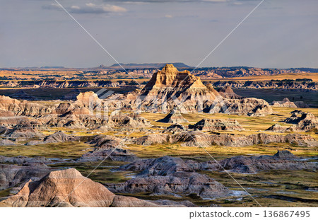Scenic landscape view of distant rugged rock formations and prairie seen from Cliff Shelf Trail at Badlands National Park, South Dakota, United States. Scenic landscape view of distant rugged rock formations and prairie seen from Cliff Shelf Trail at Badlands National Park, South Dakota, United States. 136867495