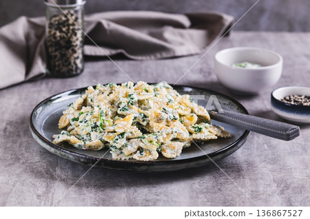 Appetizing farfalle with ricotta and spinach on a plate on the table 136867527