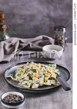 Appetizing farfalle with ricotta and spinach on a plate on the table vertical view Appetizing farfalle with ricotta and spinach on a plate on the table vertical view 136867529