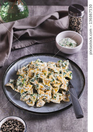 Pasta in a creamy ricotta and spinach sauce on a plate on the table vertical view 136867530