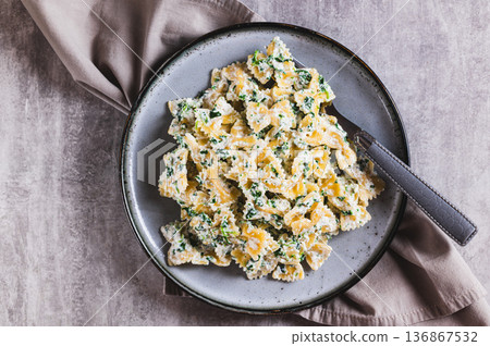 Close up of appetizing farfalle with ricotta and spinach on a plate on the table top view Close up of appetizing farfalle with ricotta and spinach on a plate on the table top view 136867532