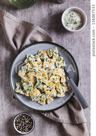 Pasta in a creamy ricotta and spinach sauce on a plate on the table top and vertical view 136867533