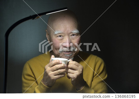 一位老人悠閒地喝著熱飲 一位老人悠閒地喝著熱飲 136868195