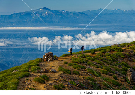 Climbers walking along the outer rim of Mt. Chokai and the view of Mt. Gassan and the Asahi mountain range Climbers walking along the outer rim of Mt. Chokai and the view of Mt. Gassan and the Asahi mountain range 136868603