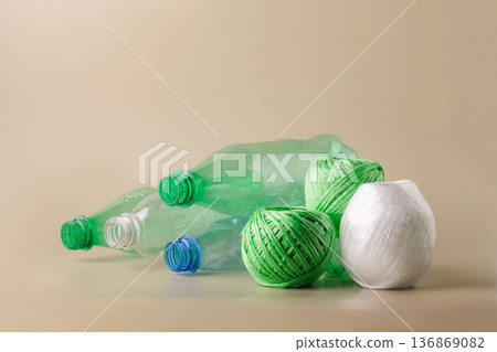 Plastic bottles balls of yarn on light background, symbolizing the eco-friendly process of recycling waste into textiles. Sustainable living, plastic recycling, reuse Plastic bottles balls of yarn on light background, symbolizing the eco-friendly process of recycling waste into textiles. Sustainable living, plastic recycling, reuse 136869082