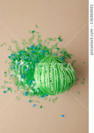 Green polyester yarn made from recycled plastic on a pile of microplastic flakes symbolizes sustainability, circular economy, and environmentally friendly production Green polyester yarn made from recycled plastic on a pile of microplastic flakes symbolizes sustainability, circular economy, and environmentally friendly production 136869083