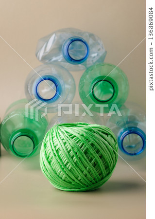 Green yarn ball and plastic bottles representing recycling 136869084