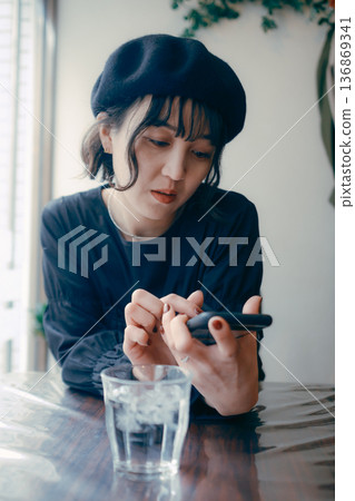 A Japanese woman in her 30s looking at her smartphone in a cafe 136869341