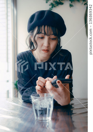 A Japanese woman in her 30s looking at her smartphone in a cafe A Japanese woman in her 30s looking at her smartphone in a cafe 136869342