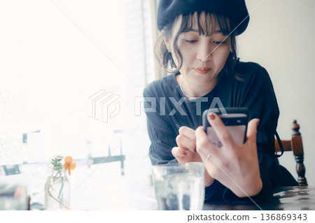 A Japanese woman in her 30s looking at her smartphone in a cafe A Japanese woman in her 30s looking at her smartphone in a cafe 136869343