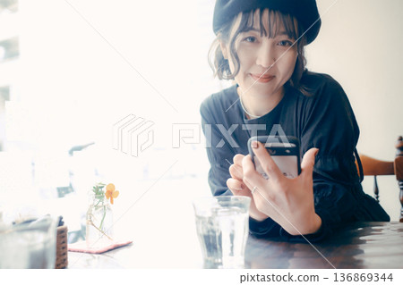 A Japanese woman in her 30s looking at her smartphone in a cafe A Japanese woman in her 30s looking at her smartphone in a cafe 136869344