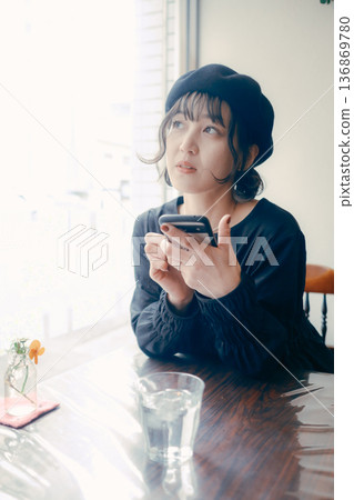 A Japanese woman in her 30s operating a smartphone in a cafe 136869780