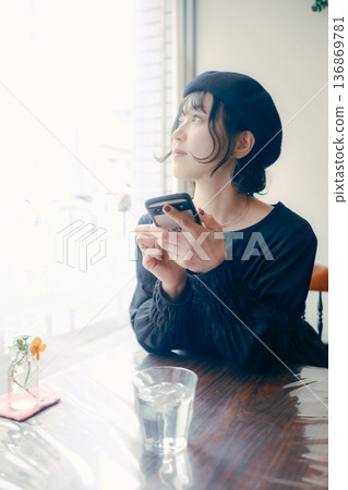 A Japanese woman in her 30s operating a smartphone in a cafe 136869781