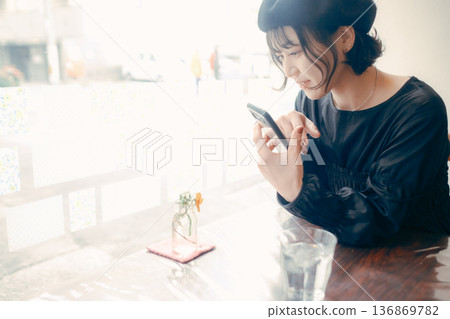 A Japanese woman in her 30s operating a smartphone in a cafe 136869782