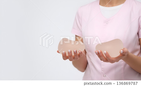Professional holds silicone breast implants while displaying options for patients considering surgery Professional holds silicone breast implants while displaying options for patients considering surgery 136869787
