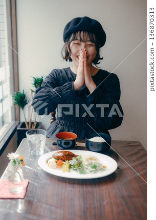 一位三十多歲的日本女性在享用漢堡牛排套餐前說“itadakimasu”（我開動了）。 136870313