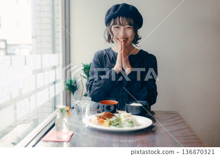 一位三十多歲的日本女性在享用漢堡牛排套餐前說“itadakimasu”（我開動了）。 136870321