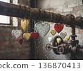 Hanging shiny hearts on a pipe during a bright light afternoon in a rustic, old building location 136870413