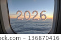 Clouds form the year 2026 as seen from an airplane window during sunset above the clouds on a flight 136870416
