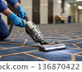 Cleaning a carpet using a vacuum cleaner in a hallway during daylight hours hotel business 136870422