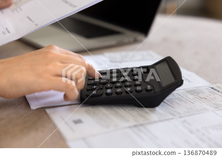 Accountant woman checking financial report on calculator 136870489