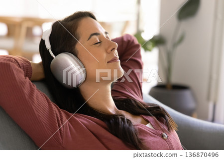 Relaxed woman listening to music in headphones Relaxed woman listening to music in headphones 136870496