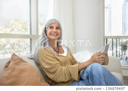 Happy woman reflecting looks aside with tablet in hands Happy woman reflecting looks aside with tablet in hands 136870497