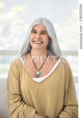 Vertical portrait of overjoyed middle-aged woman posing seated on couch Vertical portrait of overjoyed middle-aged woman posing seated on couch 136870504