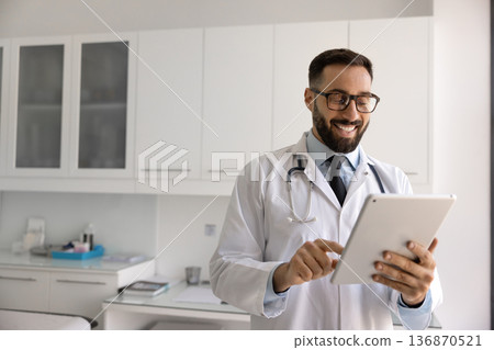 Smiling male doctor giving remote consultation online using digital tablet 136870521