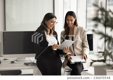 Two diverse women engaged in workflow using tablet Two diverse women engaged in workflow using tablet 136870548