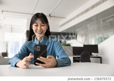 Joyful young Chinese professional woman typing on cell Joyful young Chinese professional woman typing on cell 136870572