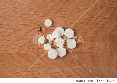 A bunch of various medicines, pills lying around without packaging on a wooden board A bunch of various medicines, pills lying around without packaging on a wooden board 136871027