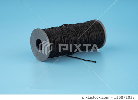 skein of black dense threads, on a blue background skein of black dense threads, on a blue background 136871032