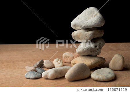 a bunch of smooth stones on a board on a black background a bunch of smooth stones on a board on a black background 136871329