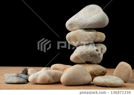 a bunch of smooth stones on a board on a black background 136871330