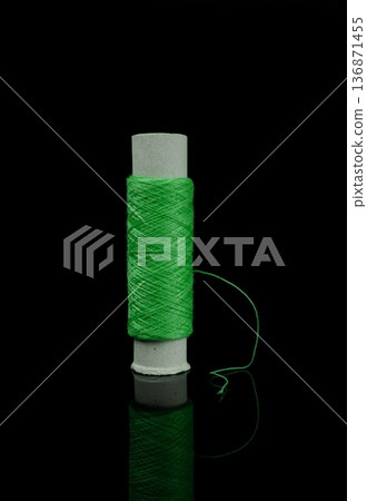 A skein of thread, a spool of thread for sewing, on a black background isolated with reflection A skein of thread, a spool of thread for sewing, on a black background isolated with reflection 136871455