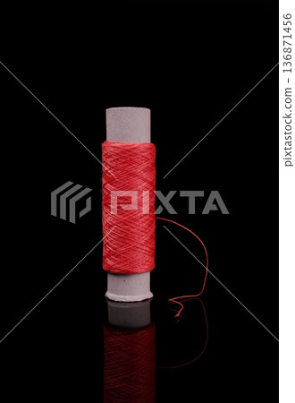 A skein of thread, a spool of thread for sewing, on a black background isolated with reflection A skein of thread, a spool of thread for sewing, on a black background isolated with reflection 136871456