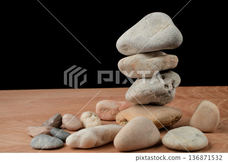 a bunch of smooth stones on a board on a black background a bunch of smooth stones on a board on a black background 136871532