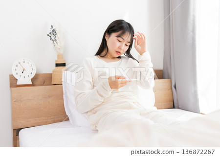 A woman who measures fever with a thermometer 136872267