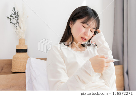 A woman who measures fever with a thermometer A woman who measures fever with a thermometer 136872271