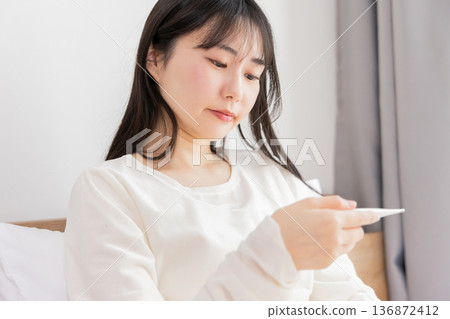 A woman who measures fever with a thermometer 136872412