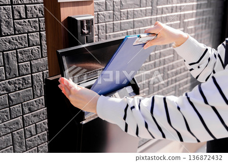 一位女士將傳單放入信箱。 一位女士將傳單放入信箱。 136872432