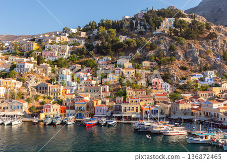 Colorful Fishing Boats In Symi Harbor With Traditional Houses And Mountains Greece 136872465