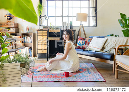 A woman in a dress sitting on a rug A woman in a dress sitting on a rug 136873472